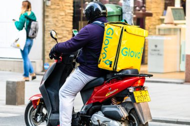 Mobiletle Glovo yemek dağıtım kuryesi. Restoranlar kapalı ve Romanya 'nın Bükreş kentindeki Coronavirus COVID-19 salgını nedeniyle acil durum döneminde sadece teslimatlara izin veriliyor.