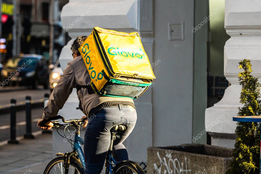 A Glovo food delivery courier on a bike. Restaurants are closed and only deliveries are allowed during the state of emergency due to coronavirus COVID-19 outbreak in Bucharest, Romania, 2020