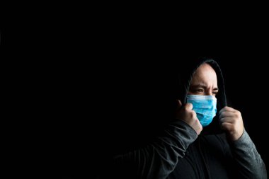 Tıbbi koruyucu yüz maskesi olan beyaz bir genç adam siyah fotokopi alanında izole edilmiş salgın koronavirüsü, Covid 19 hastalığını gösteriyor. Covid-19 salgını, grip salgını ve sağlık konsepti