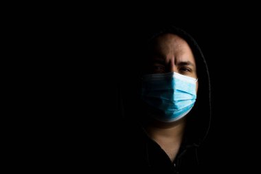 Tıbbi koruyucu yüz maskesi olan beyaz bir genç adam siyah fotokopi alanında izole edilmiş salgın koronavirüsü, Covid 19 hastalığını gösteriyor. Covid-19 salgını, grip salgını ve sağlık konsepti