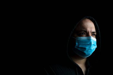 Tıbbi koruyucu yüz maskesi olan beyaz bir genç adam siyah fotokopi alanında izole edilmiş salgın koronavirüsü, Covid 19 hastalığını gösteriyor. Covid-19 salgını, grip salgını ve sağlık konsepti