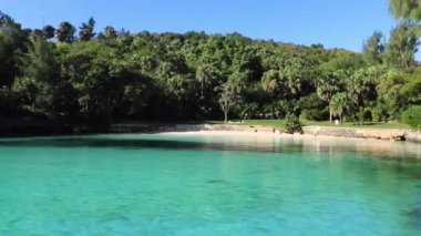 Bermuda, Hamilton, Deep Bay Beach 'te yeşil bitki örtüsüyle çevrili turkuaz ve sakin su.. 