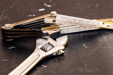 Tamir ve inşaat için aletler. Değiştirilebilir anahtar, cetvel ve enstrümanlar kopyalama alanı olan siyah ahşap masa üzerinde