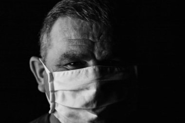 Pandemik ev izolasyonu, tıbbi koruyucu yüz maskesi olan adam siyah üzerine izole edilmiş.