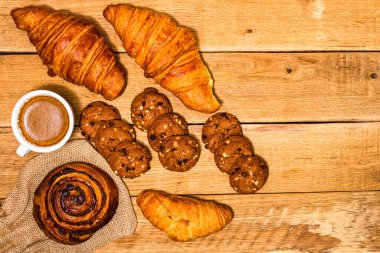 Tahta masada taze kruvasan ve bisküvi. Kahve, yemek ve kahvaltı konsepti. Tatlılar, taze hamur işleri ve kahve. Üst görünüm ve kopyalama alanı