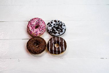 Beyaz ahşap masada renkli çörekler. Şekerli, şekerli, şekerli, şekerli, şekerli. Kopyalama alanı olan üst görünüm