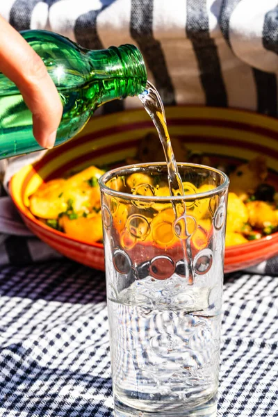 Water Uit Groene Fles Een Glas Gieten Gefrituurde Aardappelschaal Achtergrond — Stockfoto