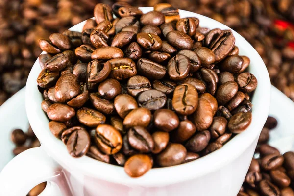 Coffee cup with roasted beans on red and coffee beans background. Close up top view, coffee concept