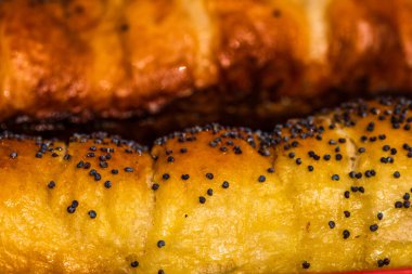 Hamurun içine tuz ve haşhaş tohumu serpiştirilmiş sosislerin detaylarını yakından incele. Sosisli börek, lezzetli ev yapımı hamur işleri..
