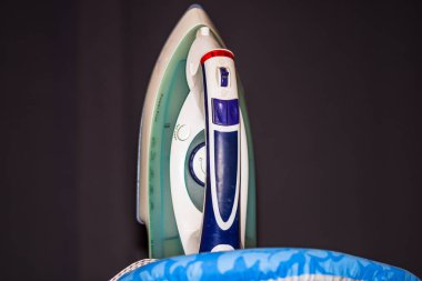 Ütü masasındaki elektrikli ütü izole edilmiş. Ev çamaşırları ütü yapıyor..