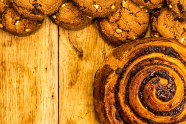 Ahşap masada renkli çörekler. Jöleli şekerli tatlı yiyecekler, çikolatalı donutlar. Kopyalama alanı olan üst görünüm