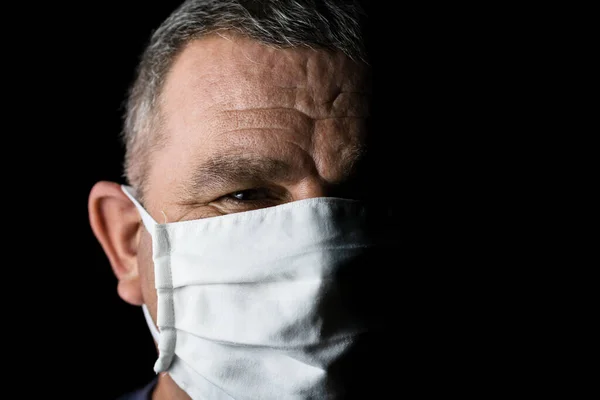 Pandemic home isolation, man with medical protective face mask isolated on black with copy space