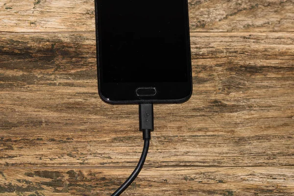 Close Bateria Carregamento Smartphone Preto Com Cabo Usb Mesa Madeira — Fotografia de Stock