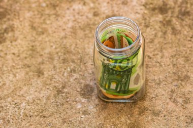 Cam bir kavanozda para biriktirme kompozisyonu. Yatırım yapma ve para tutma kavramı, tecrit edilmiş..