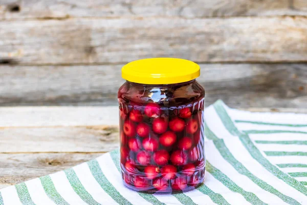 Glass jar with canned cherries fruits. Preserved fruits concept, canned fruits compote isolated in a rustic composition.