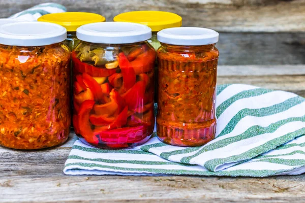 Jars with variety of canned vegetables and fruits, jars with zacusca. Preserved food concept in a rustic composition.