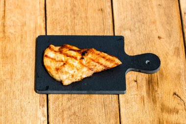 Izgara bifteği, izole edilmiş küçük siyah kesme tahtasına yakın tut. Barbekü, ızgara ve yemek konsepti.