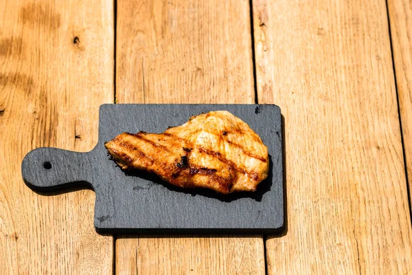 Izgara bifteği, izole edilmiş küçük siyah kesme tahtasına yakın tut. Barbekü, ızgara ve yemek konsepti.