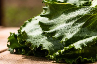Tahta bir masanın üzerindeki taze yeşil marulun detaylarını kapat..