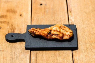 Izgara bifteği, izole edilmiş küçük siyah kesme tahtasına yakın tut. Barbekü, ızgara ve yemek konsepti.