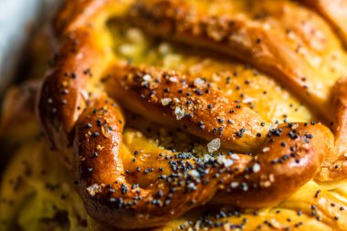 Örülmüş poğaça üzerine tuz ve haşhaş tohumlarının detaylarına odaklanmış seçici bir fotoğrafla kapat..