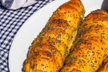 Hamurda pişmiş sosisler tuzlu ve haşhaş tohumları serpiştirilmiş, kırsal bir kompozisyonda. Sosisli börek, lezzetli ev yapımı hamur işleri..