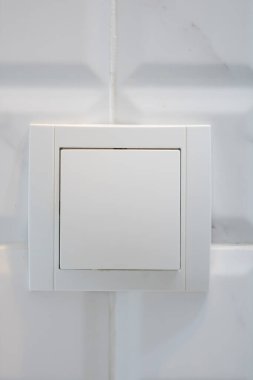 Beyaz fayansın üzerindeki beyaz elektrik düğmesini kapat. İnşaat elemanları konsepti, iç tasarım.