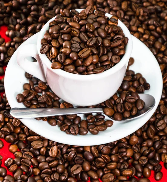 Coffee cup with roasted beans on red and coffee beans background. Close up top view, coffee concept