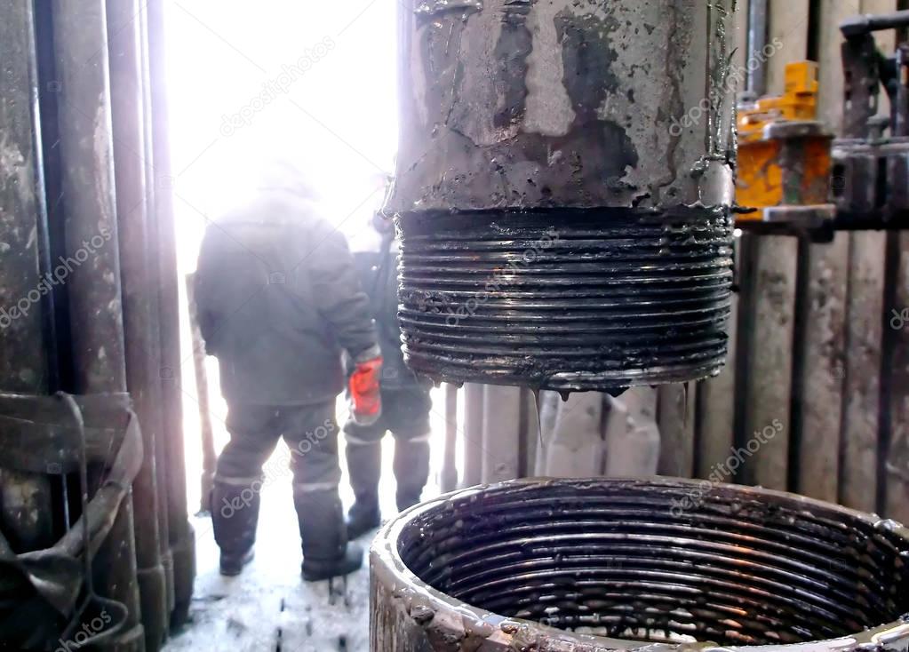 downstream of a pipe for oil production. Drilling an oil well inside a drilling rig. The process of drilling a well.