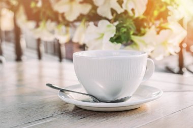 Günbatımı ışığında ahşap masanın üzerinde, fotokopi alanı olan büyük beyaz kahve fincanı..