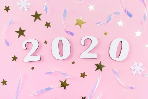 Ξύλινα 2020 αριθμούς και διακοσμήσεις Χριστουγέννων, κομφετί, αστέρια και νιφάδες χιονιού σε ανοιχτό ροζ φόντο. — Φωτογραφία Αρχείου