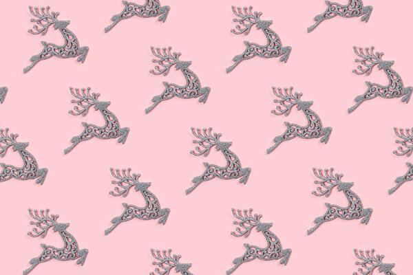 Pattern made of white christmas deer decoration on pastel pink background. Christmas concept.