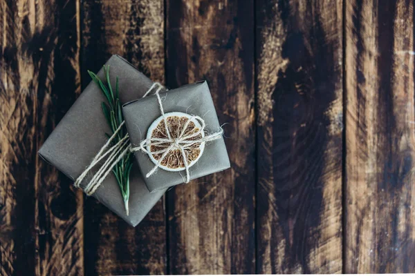 Geschenke und Geschenke verpackt in Bastelpapier mit Dekoration auf braunem Holzgrund. Konzept "Ferien ohne Abfall". — Stockfoto