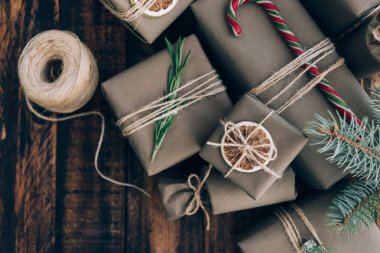 Hediyeler ve hediyeler kahverengi ahşap arka planda süslemeli el sanatları kağıdına sarılı. Tatil sıfır atık kavramı.