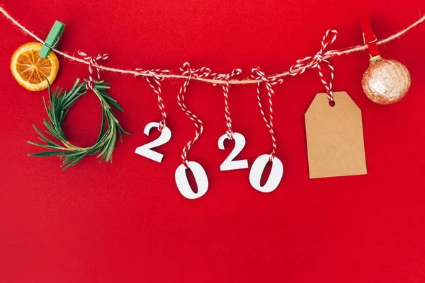 Χριστουγεννιάτικες χειροποίητες γιρλάντες από ξύλο το 2020 και κλαδιά ελάτης και άλλες χριστουγεννιάτικες διακοσμήσεις σε κόκκινο φόντο. — Φωτογραφία Αρχείου