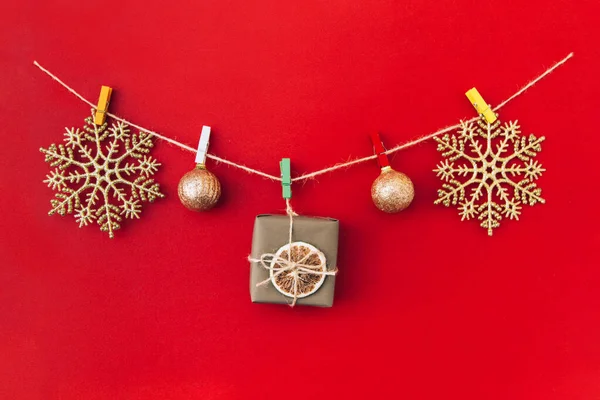 Weihnachten handgemachte Girlande aus goldenen Schneeflocken und anderen Weihnachtsdekorationen auf rotem Hintergrund. — Stockfoto