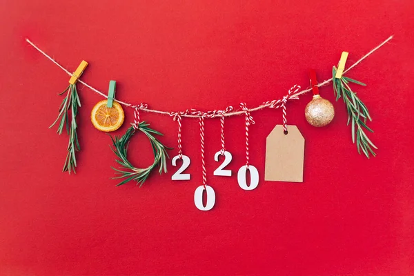 Weihnachten handgefertigte Girlande aus 2020 Holzziffern und Tannenzweigen und anderen Weihnachtsdekorationen auf rotem Hintergrund. — Stockfoto