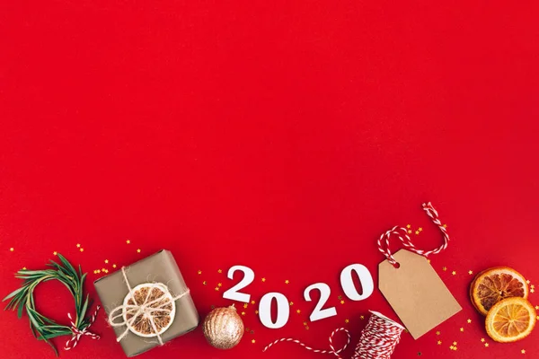 Guirnalda de Navidad hecha a mano de números de madera 2020 y ramas de abeto y otras decoraciones de Navidad sobre fondo rojo. Navidad, Año Nuevo, concepto de cero residuos . —  Fotos de Stock