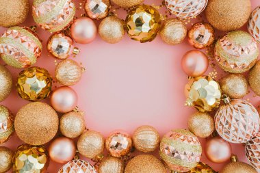Parlatıcılardan yapılmış çerçeve ve soluk pembe arka planda altın Noel ağacı topları.