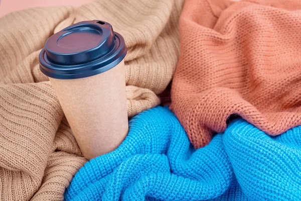 Καφετιέρα χάρτινη κούπα σε πολύχρωμες πλεκτές κουβέρτες φόντο, πάνω όψη επίπεδη lay. — Φωτογραφία Αρχείου