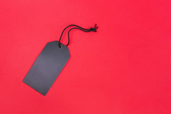 Leeres schwarzes Etikett auf rotem Hintergrund mit Kopierraum. Preisschild, Geschenketikett, Verkaufsetikett, Adressetikett usw.. — Stockfoto