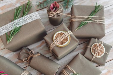 Beyaz ahşap arka planda süslemeleri olan el sanatları kağıdına sarılı hediyeler. Tatil sıfır atık kavramı.