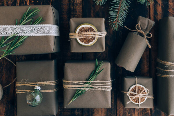 Подарки и подарки, завернутые в ремесленную бумагу с отделкой на коричневом деревянном фоне. Концепция нулевых отходов
.