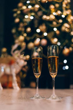 Bulanık dekore edilmiş Noel ağacının arkasında duran iki kadeh şampanya..