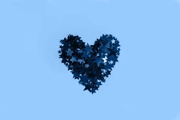 Delicado brilho estrela confete em forma de coração no fundo azul . — Fotografia de Stock