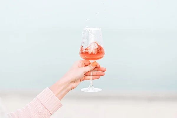 Glass of rose wine in female hand against the seashore. — Stock Photo, Image