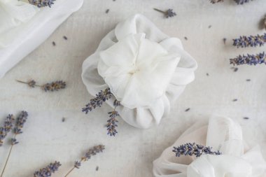 Beyaz furoshiki kumaşıyla sarılmış ve lavanta çiçekleriyle süslenmiş bir hediye. Çevre dostu hediye..