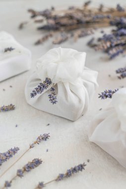 Beyaz furoshiki kumaşıyla sarılmış ve lavanta çiçekleriyle süslenmiş bir hediye. Çevre dostu hediye..