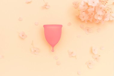 Turuncu arka planda ortanca çiçekli regl bardağı..