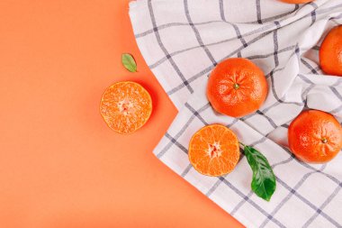 Turuncu arka planda yeşil yapraklı taze mandalinalar..